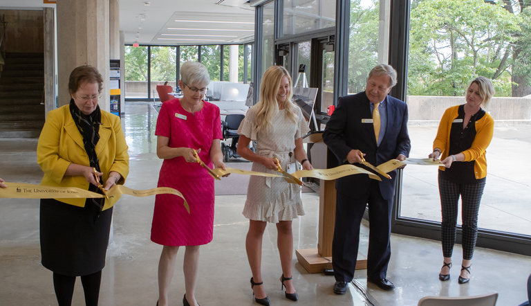 five people in line cutting a ribbon