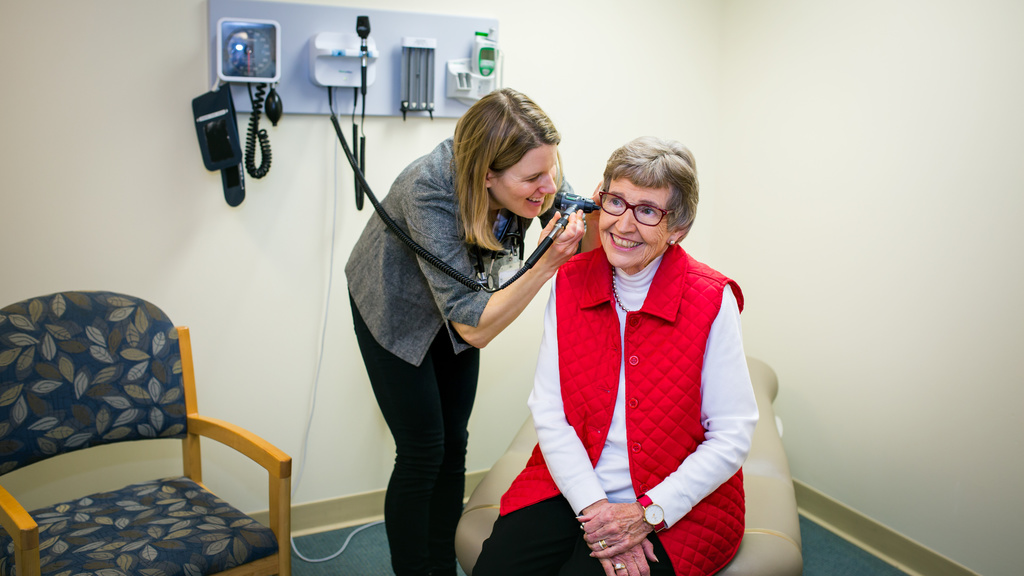 nurse practitioner examines patient's ear